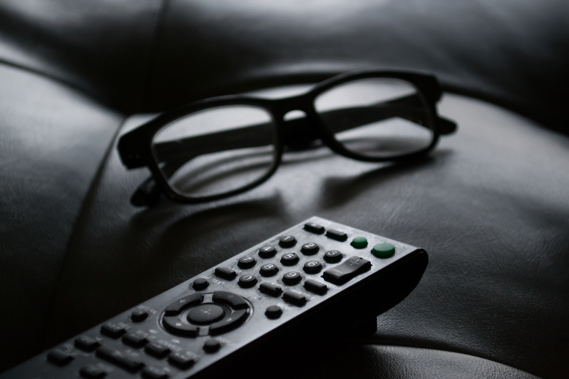 Télécommande et paire de lunettes sur canapé