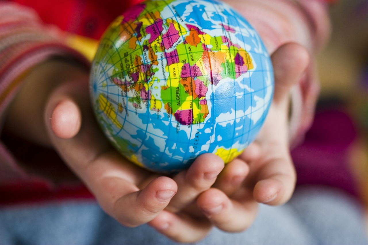 mains d'enfant tenant un globe terrestre coloré