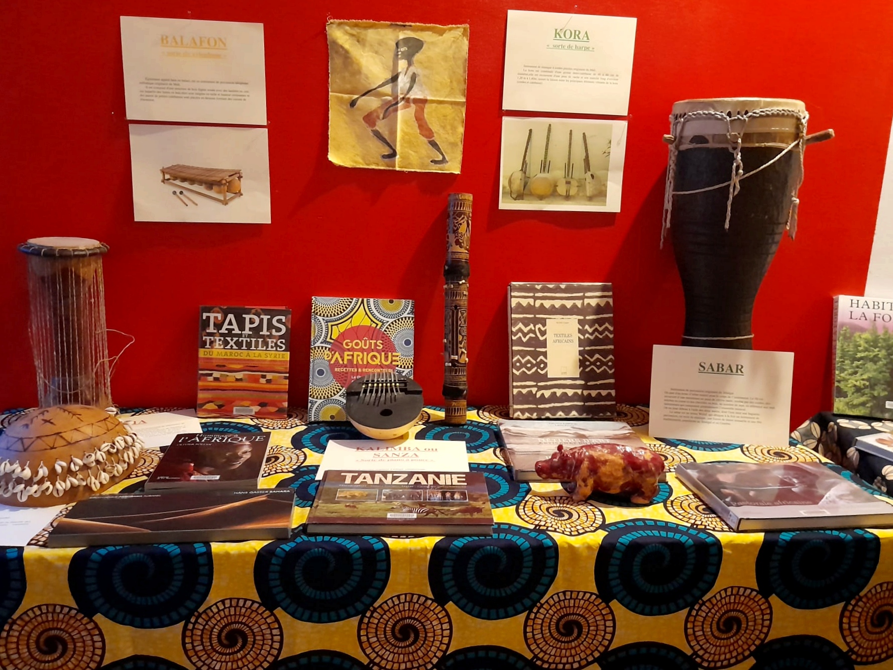 Des instruments de musique africains et des livres sur une table joliment décorée de tissus africains