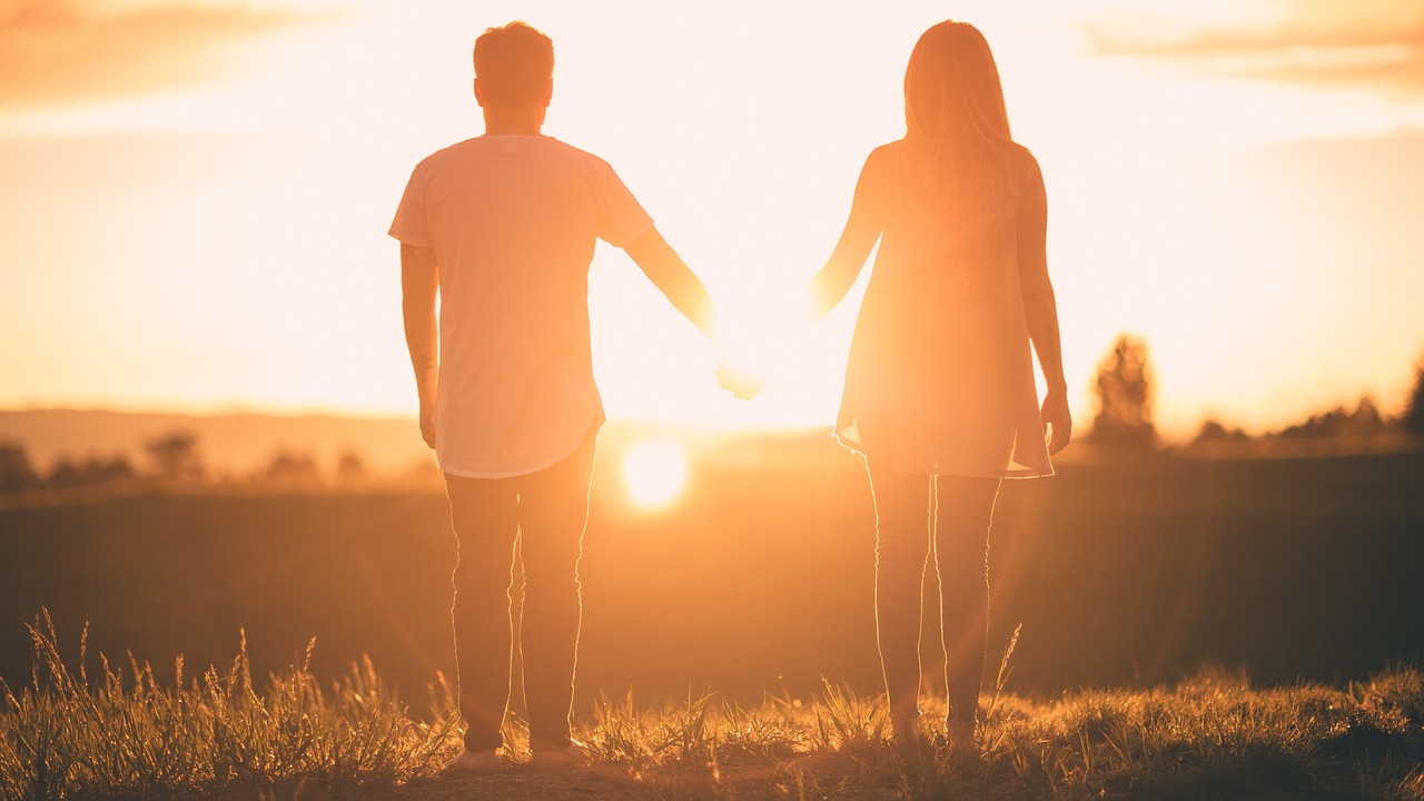 2 adolescents de dos se donnant la main sur fond de coucher de soleil