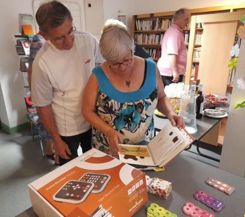 un homme et une femme feuilletant un livre adapté aux personnes malvoyantes