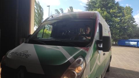 Camionnette entrant dans garage avec phares allumés, aux couleurs vertes avec logo "Puy-de-Dôme Mon Département"