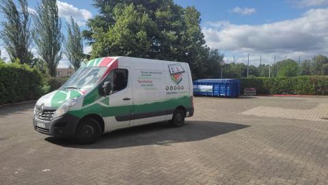 Camionnette à l'extérieur avec bandes vertes et rouges et inscriptions vertes et rouges et images de livres, homme au volant