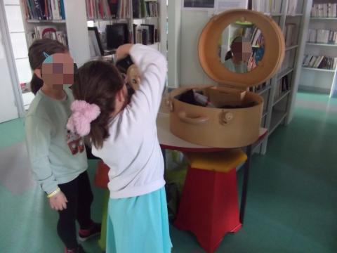 2 enfants devant une mallette en bois ouverte avec un miroir regardant devant