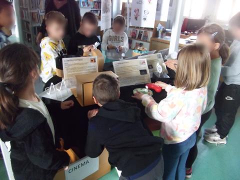 enfants autour d'une table remplie d'objets en bois et de livres qui regardent et manipulent