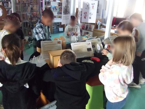 enfants autour d'une table remplie d'objets en bois et de livres qui regardent et manipulent