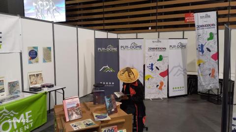 Personne avec un chapeau japonais qui lit dans le stand de la Médiathèque départementale dans la Geek Convention