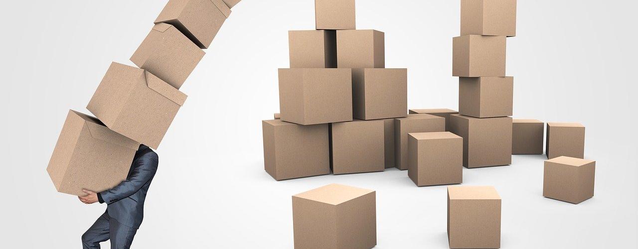 homme portant une pile de cartons