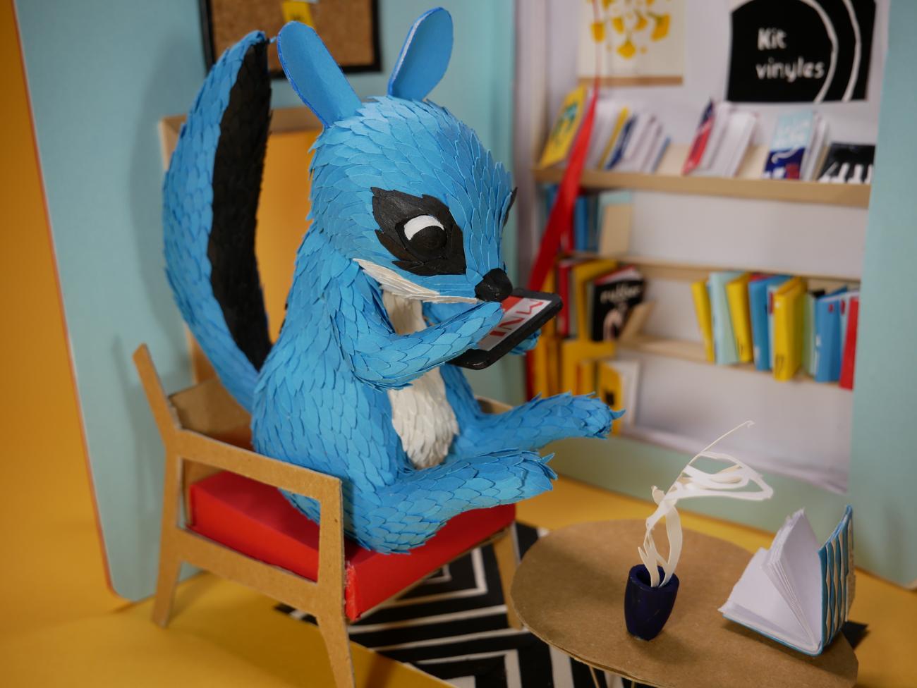 sculpture écureuil bleu lisant assis sur une chaise