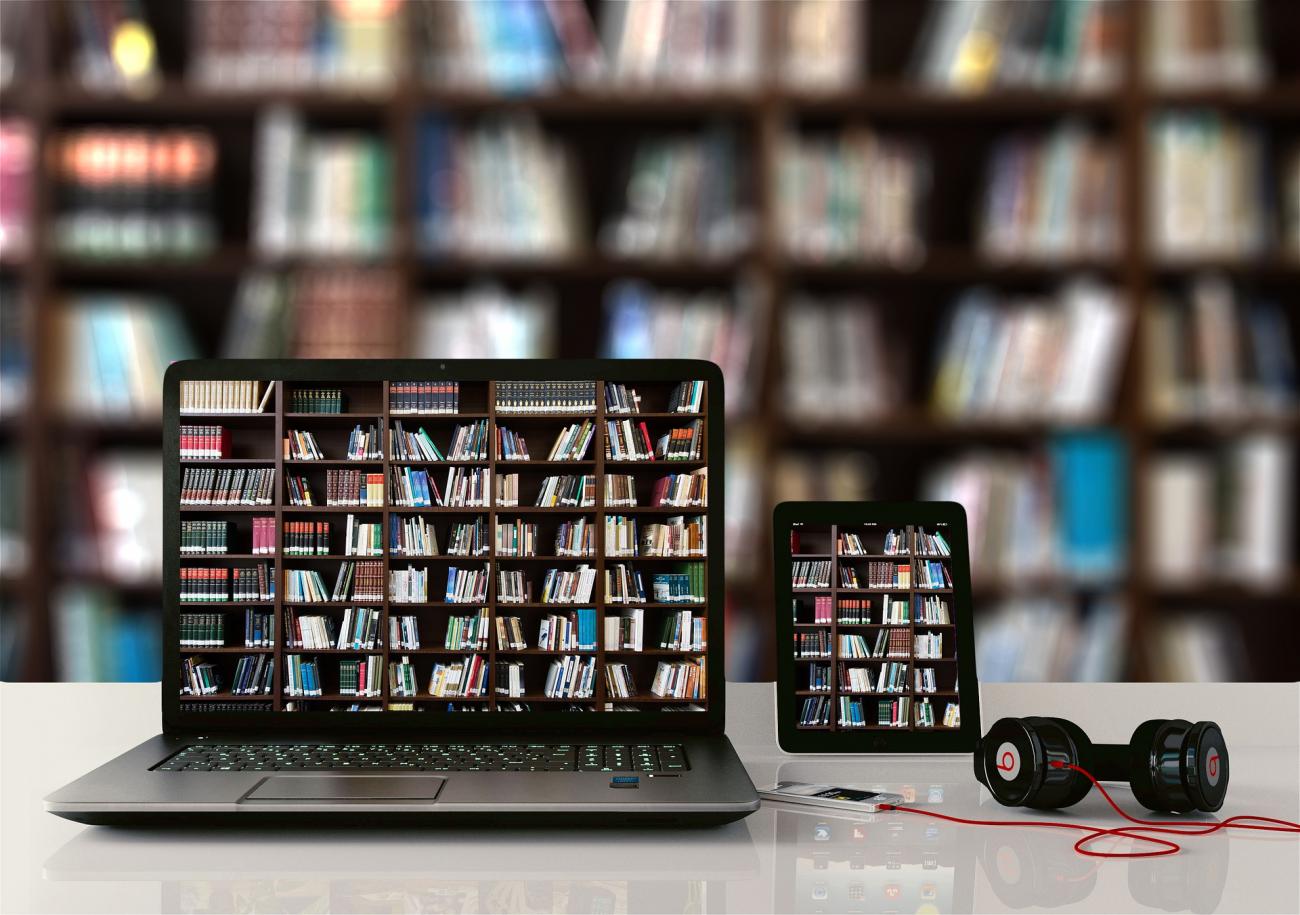 Ordinateur et tablette devant une bibliothèque