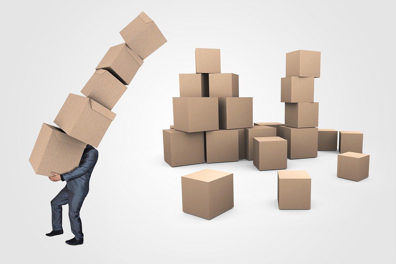 homme portant une pile de cartons