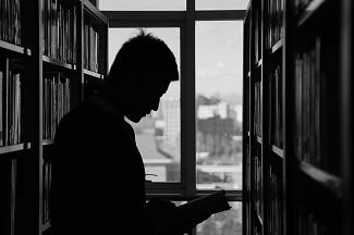 Silhouette d'un homme lisant en bibliothèque (PIXABAY)