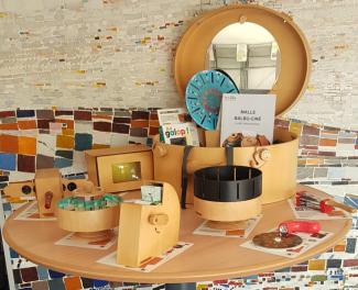 photo des différents objets de la malle balbu ciné en bois avec malle ovale ouverte sur table ronde