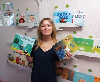 Photo d'Anaïs entourée des albums de la collection Ouvrez, ouvrez les livres aux bébés