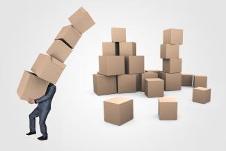 homme portant une pile de cartons