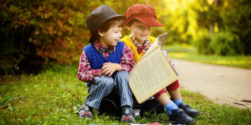 deux enfants en train de lire dans un parc