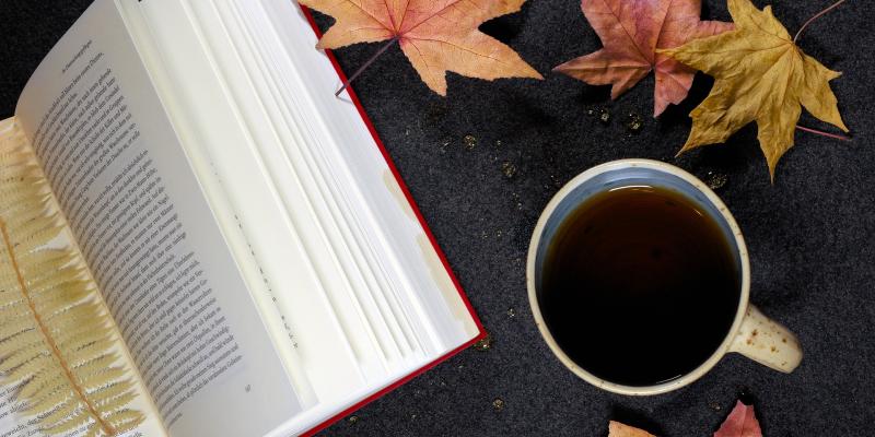 Livre ouvert, feuilles d'érable et tasse de café