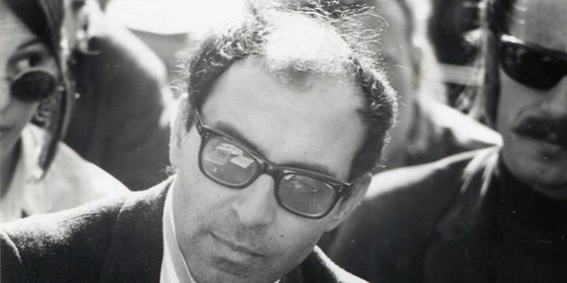 photo en noir et blanc du visage de Jean-Luc Godard avec lunettes de soleil